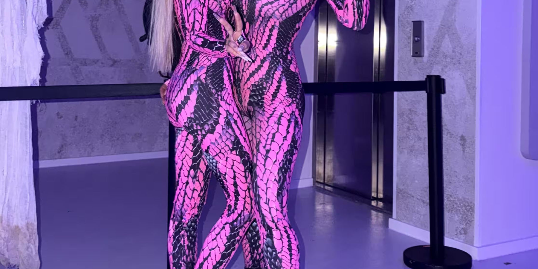 Two women wearing matching pink and black snakeskin catsuits with black platform boots, posing together in Halloween rave outfits for MÁS EDM Los Angeles.