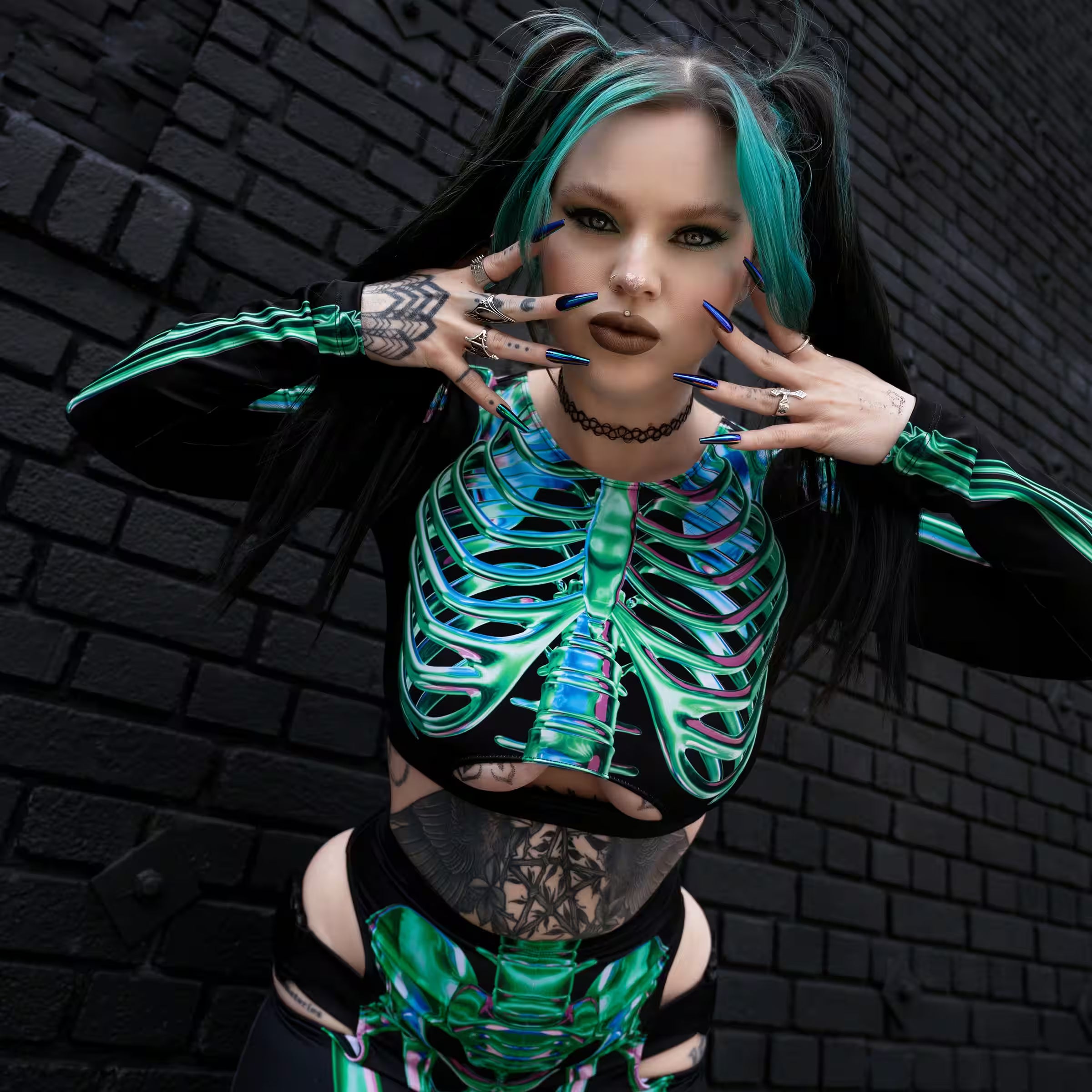 Woman wearing a black Halloween rave outfit with metallic green and blue skeleton print, cut-out details, and turquoise hair, styled for MÁS EDM Nashville.