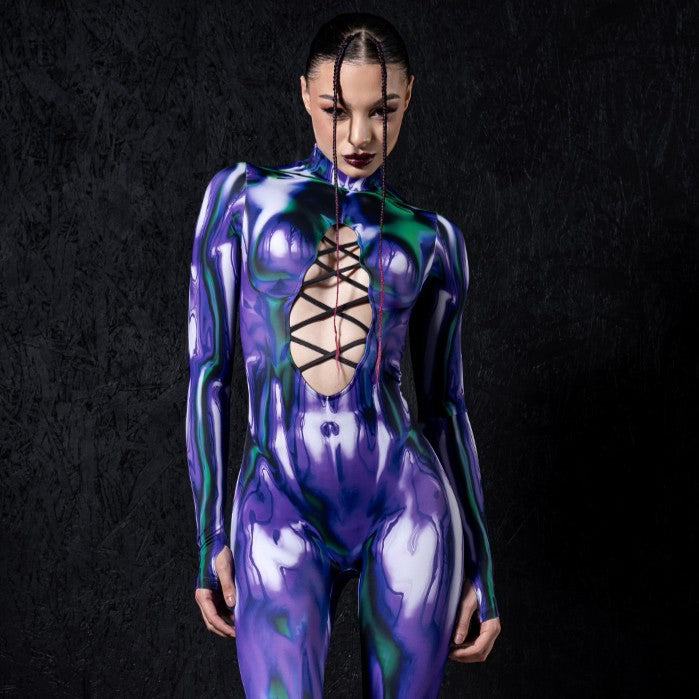 Woman wearing a purple and green metallic-print bodysuit with a lace-up chest cutout and black platform boots.