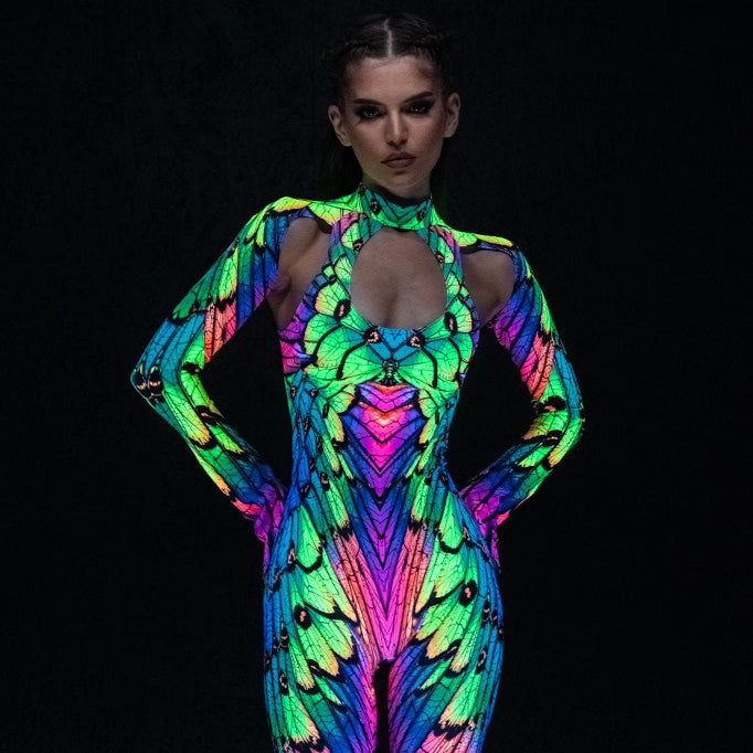 Woman wearing a vibrant neon butterfly-print bodysuit with chest and shoulder cutouts, paired with black platform boots.