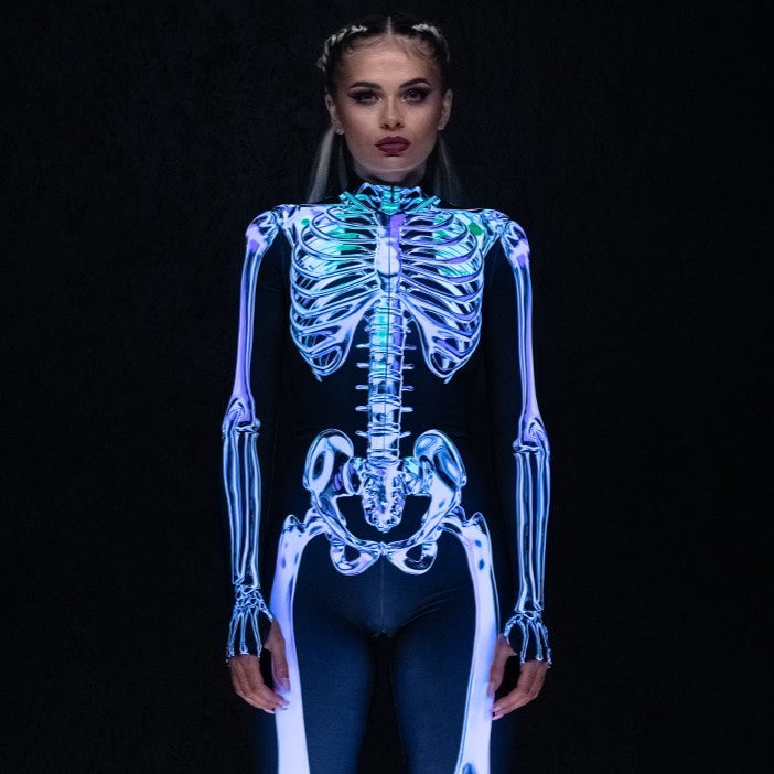 Woman wearing a black bodysuit with a glowing blue and silver skeleton print, paired with black platform boots.
